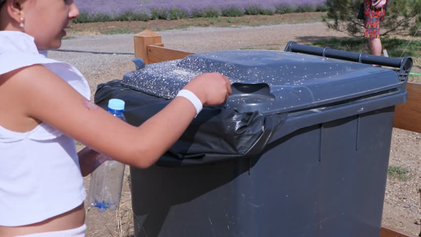A young girl throwing a plastic bottle into a recycling bin