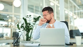 Sick businessman in light blue shirt coughs painfully at modern office desk. Suffering from illness, male employee shows discomfort while working on laptop, feeling tired. - Powered by Shutterstock - Get 15% off with code: PIKWIZARD15