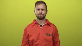 Man prisoner with beard wearing orange jumpsuit stamped 382586 standing in lime studio with neutral expression, eyes closed; quiet reflection solitude. - Powered by Shutterstock - Get 15% off with code: PIKWIZARD15