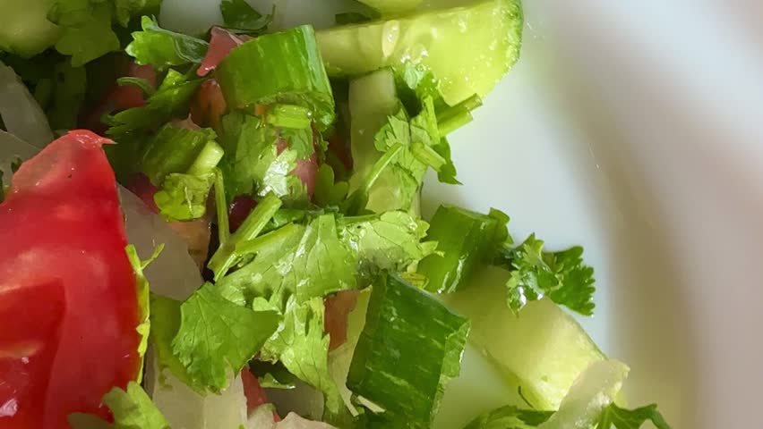 Macro shot of a salad with fresh vegetables and herbs. Freshly made Mediterranean salad on plate. 
