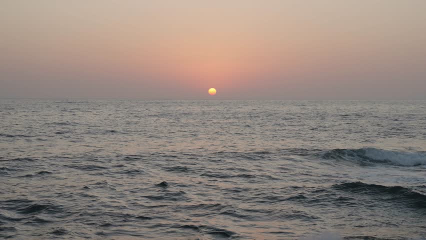 Sea waves crushing on a rocky beach at sunset