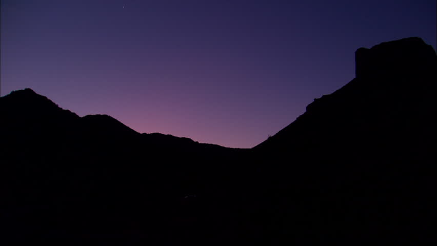 Still shot of the mountains silhouetted against a purple sunrise