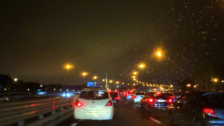 Dashcam view of a car driving through the streets of Moscow, Russia. Urban road traffic scene with moving vehicles, cloudy weather, and street lights. Concept of transportation, pov