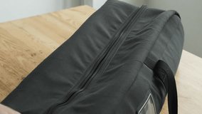 Close-up hand zipping a black padded travel bag on wooden table - Powered by Shutterstock - Get 15% off with code: PIKWIZARD15