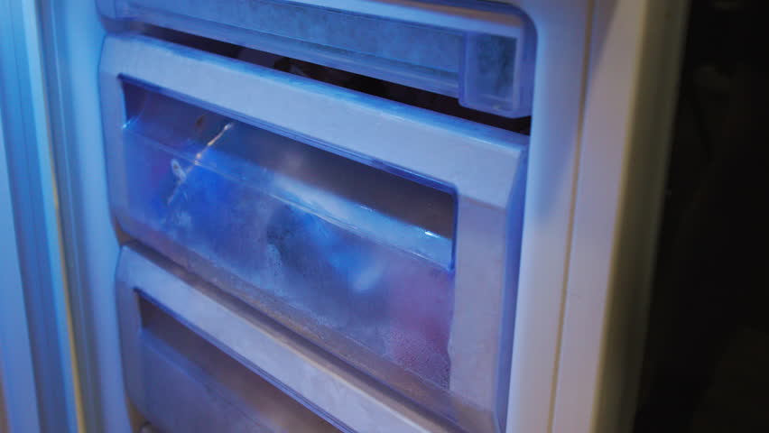 Opening Frosty Freezer Drawer with Frozen Food Bags Under Blue Light