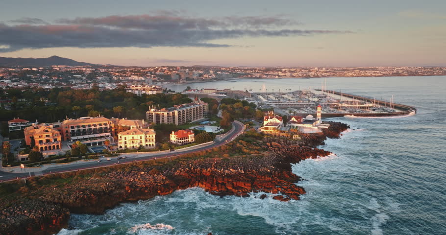 Portugal, Lisbon: Cascais coastal town with Santa Marta Lighthouse and marina bathed in golden light during colorful bright sunset, Iberian Peninsula