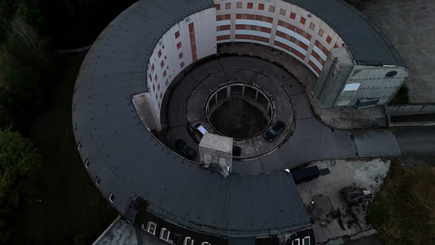 Drone video shows half-finished circular building under construction, symbolizing development, architecture, and urban transformation.
