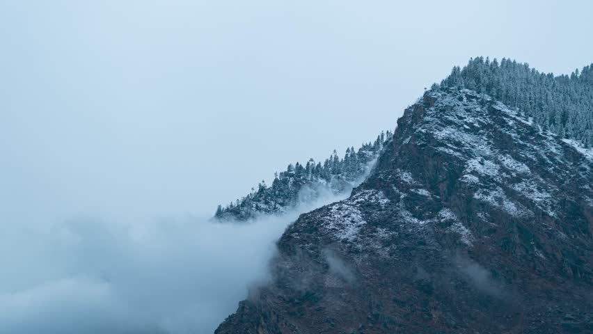 4K Zoom in Time lapse shot of dark clouds rolling in mountains after first snowfall in mountains at Manali, Himachal Pradesh, India. First Snowfall, Fresh and Serene Winter Weather. 
