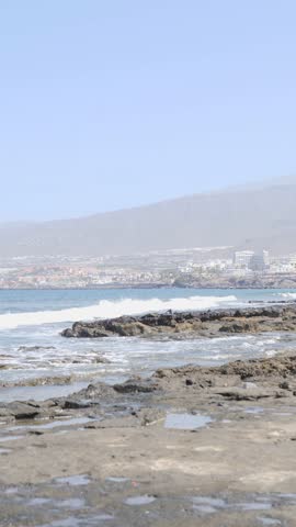 A captivating scenic coastal view showcases a rocky shoreline and a distant city in the background