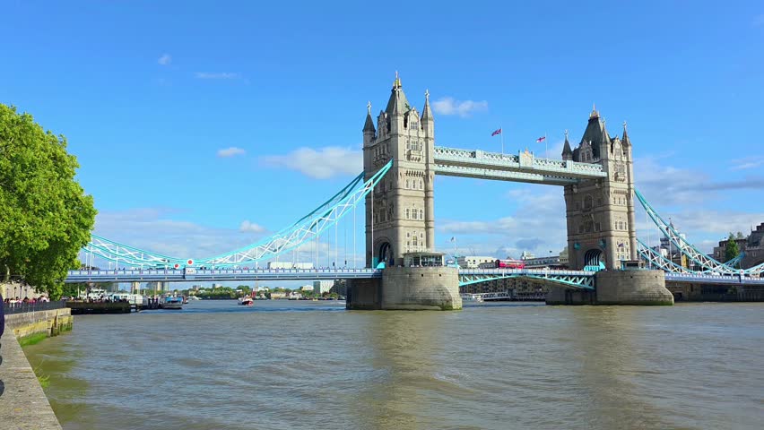 Summer view of the iconic Tower Bridge across the Thames, London, UK. Handheld, panning motion.