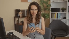 Woman smiling as she taps smartphone with fingers while seated at desk in building office; contentment engagement concentration communication. - Powered by Shutterstock - Get 15% off with code: PIKWIZARD15