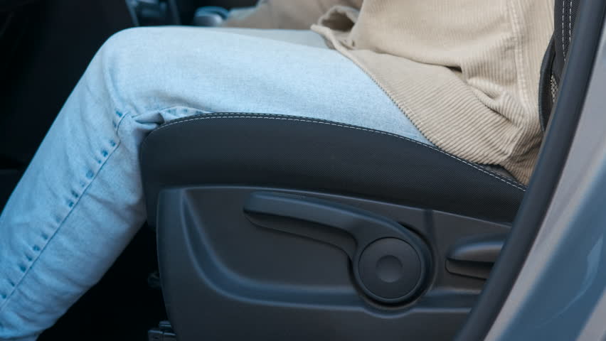 Woman adjusting car seat lever. Woman carefully positioning herself in driver's seat, methodically adjusting seat lever for optimal comfort and ergonomic driving posture inside vehicle