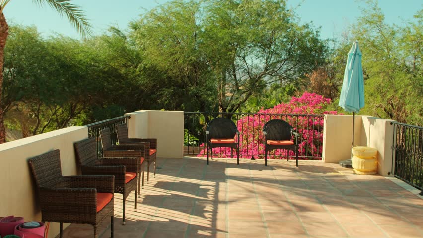 Beautiful back patio with pink flowers, palm springs, lounge chairs, yoga mats on a sunny day