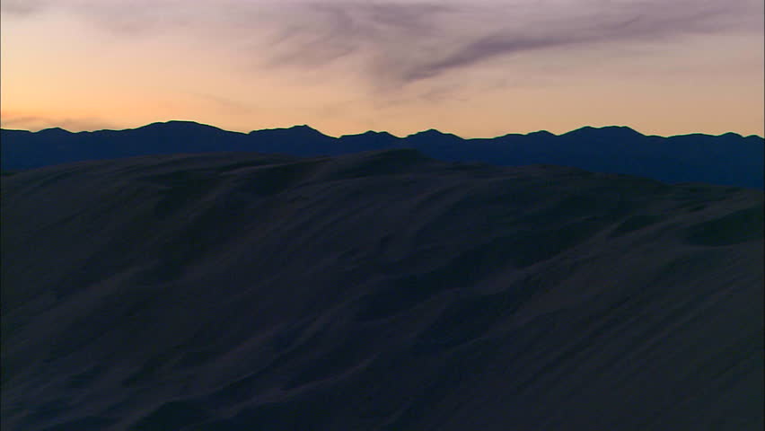 Pan across desert mountains at sunset