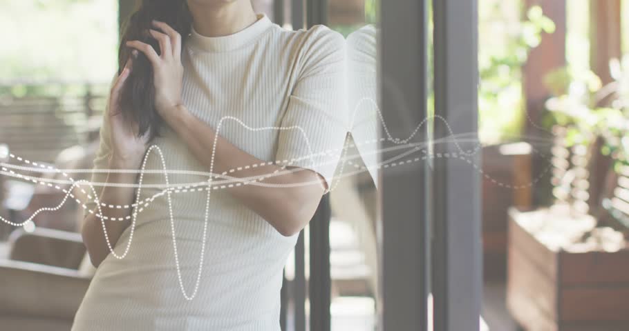 Woman raising hand brushing hair near glass door activating waveform graphic showing audio tech. Modern, contemplative, serene, minimalistic, digital, introspective, lifestyle