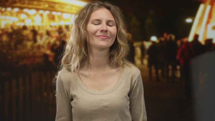 Woman face smiling night carnival lights blonde portrait outdoor casual snapshot capturing festive vibe.