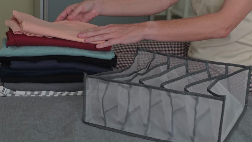 Close up of woman hands folded clothes and organize laundry in the bedroom
