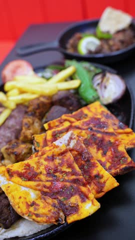 Close-up of a mixed grill platter with kebabs, fries, and flatbread served in a restaurant setting. Perfect for food promos, menu visuals, and Middle Eastern cuisine ads.