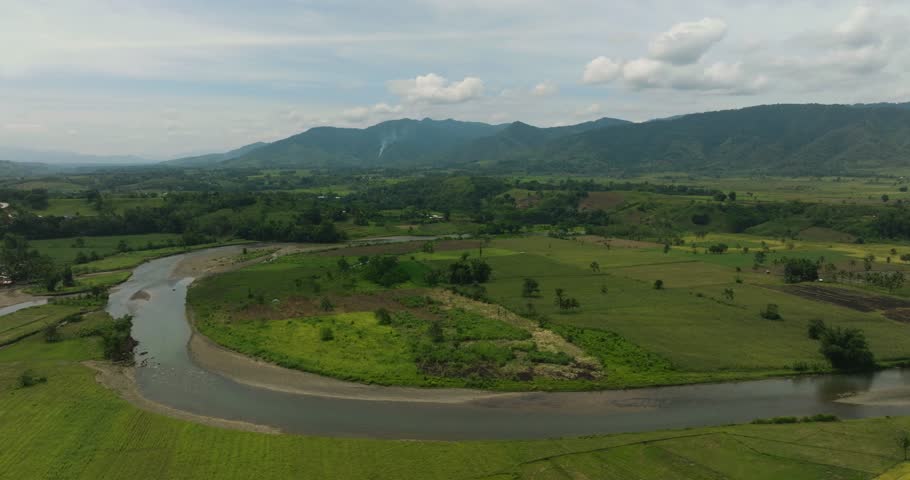 Rice fields, paddy farms and riverbanks. Blue sky and clouds. Mindanao, Philippines.