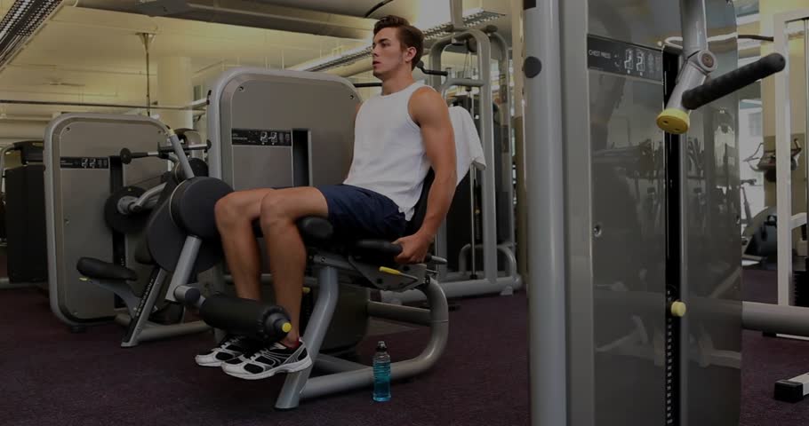 Fitness trainee settling on leg extension machine, performing knee extensions for leg strength. Gym, strength, workout, fitness, training, athletic, exercise