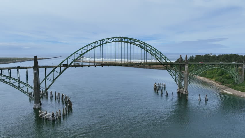 Drone rising over the Yaquina Bay Bridge, toward the beach in cloudy Newport