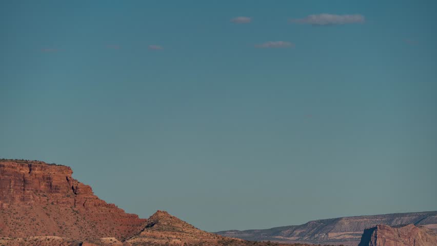 Timelapse of the full moon rising over a desert rock formation cloudless sky