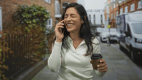 Woman talking on phone holding coffee cup while walking briskly down a city street past brick building and delivery van; morning commute joy. - Powered by Shutterstock - Get 15% off with code: PIKWIZARD15