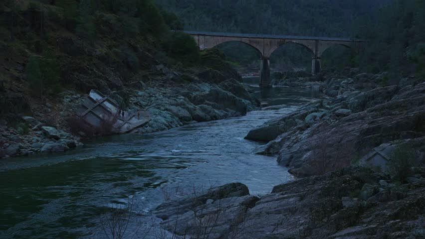 Bridge over a mountain river among rocks at sunset