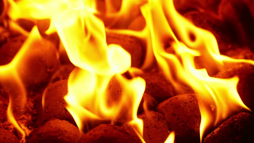 Close-Up of Fiery flames burning coal briquettes preparing BBQ grill