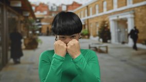 Young chinese woman in a vibrant green top playfully boxing in an urban street setting, showcasing energy and confidence in the city outdoors. - Powered by Shutterstock - Get 15% off with code: PIKWIZARD15