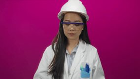 Young chinese woman architect studies blueprints wearing hardhat against isolated pink background, focusing intently on construction plans with a vibrant wall enhancing the scene. - Powered by Shutterstock - Get 15% off with code: PIKWIZARD15
