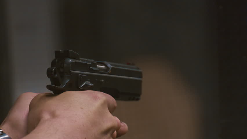 Man soldier shoots a gun at a shooting range. Modern army, real weapons. Male is makes a shot, wearing headphones. slow motion. Aiming at the target. Military units in shooting gallery using pistols