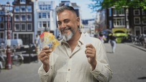Middle aged man holds a fan of swiss franc banknotes and a white card on a busy city street with bicycles and buildings; confidence prosperity. - Powered by Shutterstock - Get 15% off with code: PIKWIZARD15