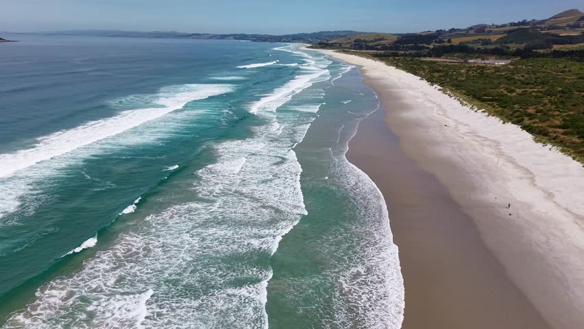 Reverse motion drone videos reveals breathtaking background seascape of Pacific ocean coastline in marvellous New Zealand with rolling waves, white water and green foliage
