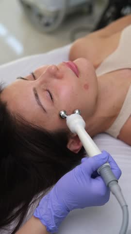 Cosmetologist performing a micro current therapy facial rejuvenation treatment to a mature woman in a beauty clinic. Doctor uses electrical pulses for cosmetic procedures enhancing skin appearance