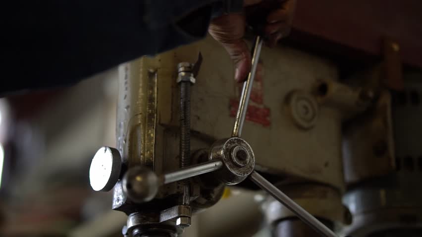 Metalworker Operating an Old Industrial Drill Press Machine in a Workshop
