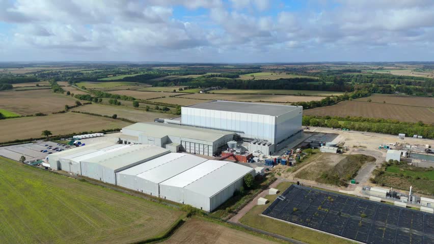 Aerial view of industrial buildings with silver roofs contrasted by the green fields and blue sky, Nottingham, England, United Kingdom.
