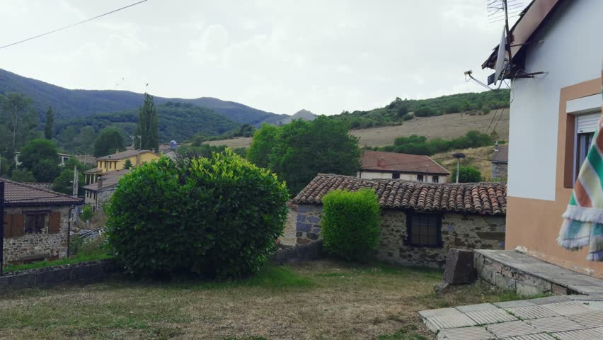 Slow panning shot revealing a picturesque traditional village with stone houses in a mountain valley