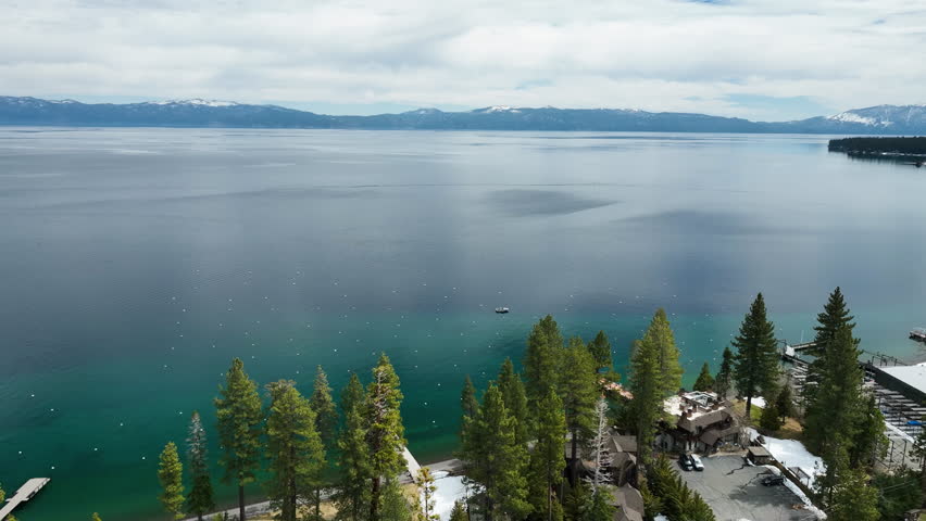 Panoramic drone shot circling the coastline of Lake Tahoe, spring day in USA