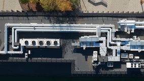 Top-down aerial view of an industrial rooftop HVAC system in Kaunas, Lithuania, featuring extensive ductwork, pipes, and cooling units, surrounded by urban autumn landscape, zooming out. - Powered by Shutterstock - Get 15% off with code: PIKWIZARD15