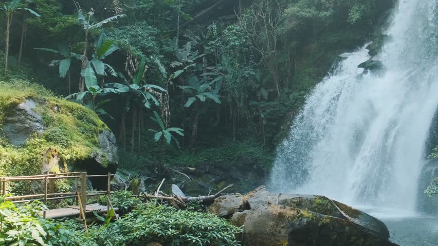 Powerful waterfall cascading down rugged cliffs deep within the lush rainforest of Doi Inthanon National Park, Chiang Mai, Thailand. Ecotourism, wilderness exploration and environmental conservation