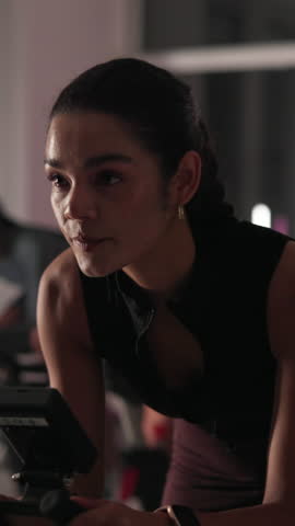 Bike, training and woman in gym, sweating and night with equipment, workout and challenge. Healthy people, endurance and machine in club, exercise and breathing with wellness, fitness and cycling