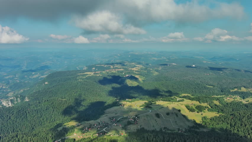 Aerial view on mountains, hills and meadow, village under clouds in Tara national park, Serbia, 4k