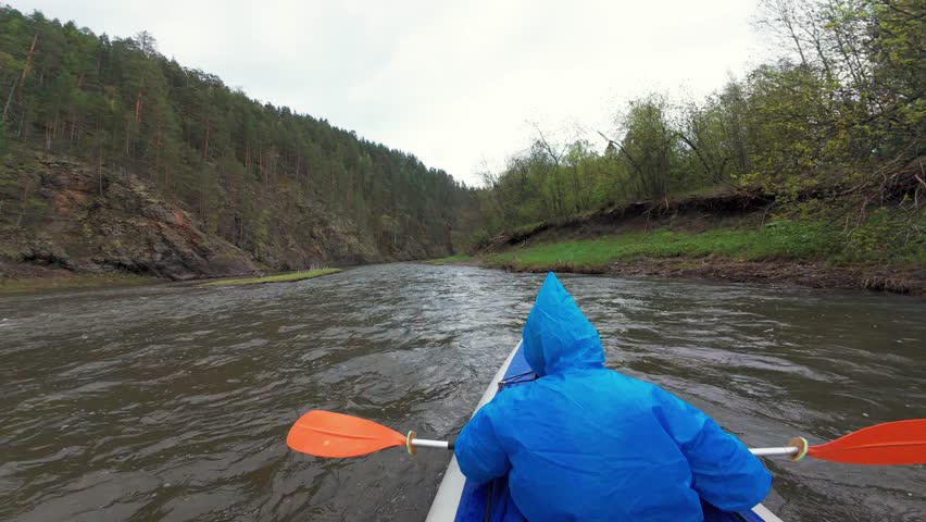 Experience the exhilarating thrill of kayaking through a lush and picturesque river canyon, surrounded by towering cliffs and vibrant greenery, all while under a beautifully cloudy and rainy sky