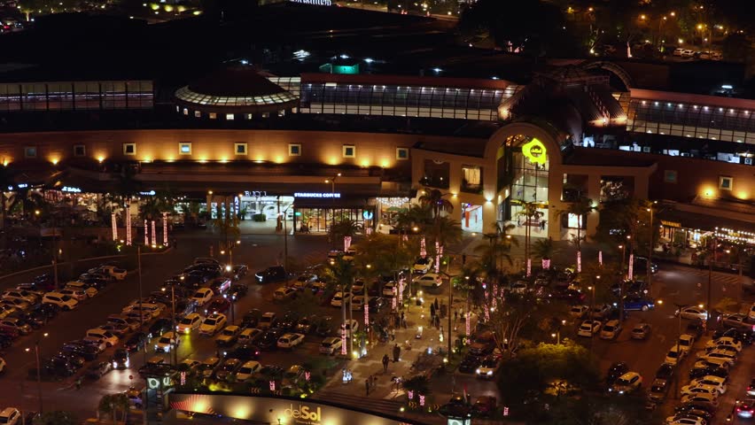 An illuminated night aerial view of Shopping del Sol Mall in Asuncion, Paraguay, with parking area below