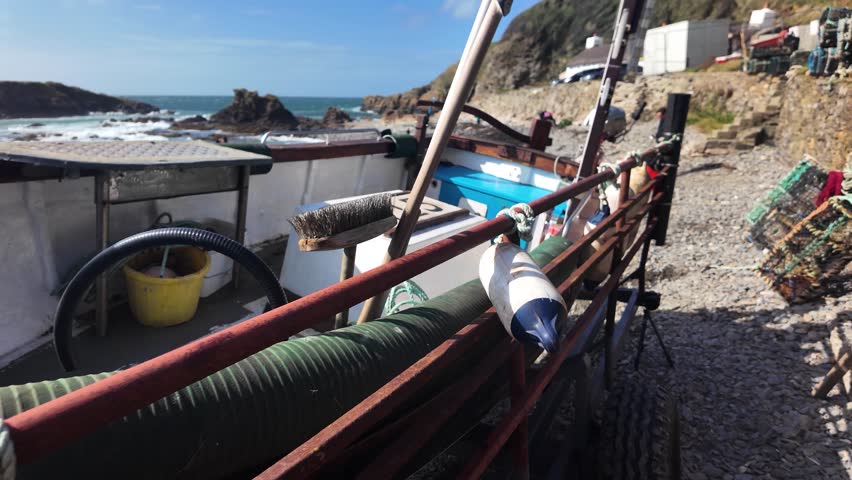 Fishing boat with equipment and trailer on beach by rugged ocean coast