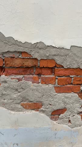 Exposed red brick wall with peeling plaster, showcasing texture and industrial background video