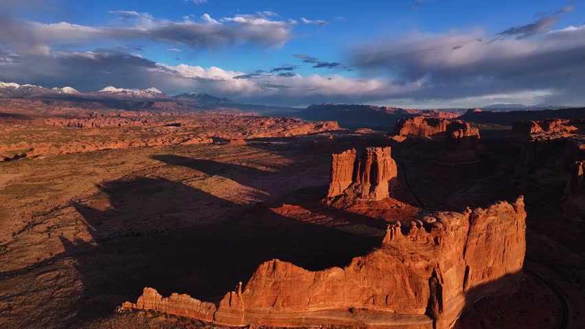 Aerial view of the sun casting long shadows across the red rock formations and canyons of Arches National Park, Grand County, United States.