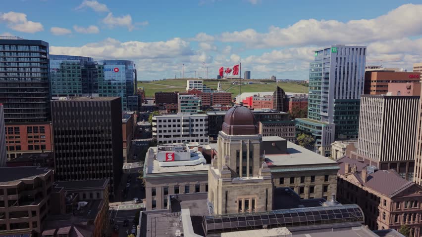 Cinematic View From Above Of A Canada Flag Proudly Standing On A Flagpole In Downtown Halifax, Nova Scotia. The Cityscape And Cloudy Skies Set A Perfect Patriotic Mood.