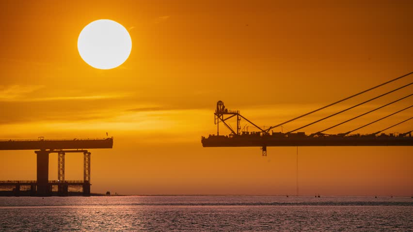 Spectacular sunset over the nearly completed Danjiang Bridge in Tamsui New Taipei Taiwan during early autumn. Golden orange and reddish pink dreamlike sky.